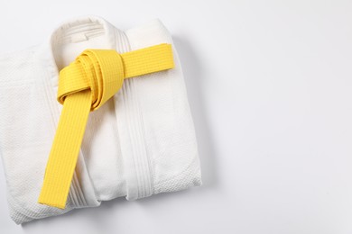 Yellow karate belt and kimono on white background, top view. Space for text