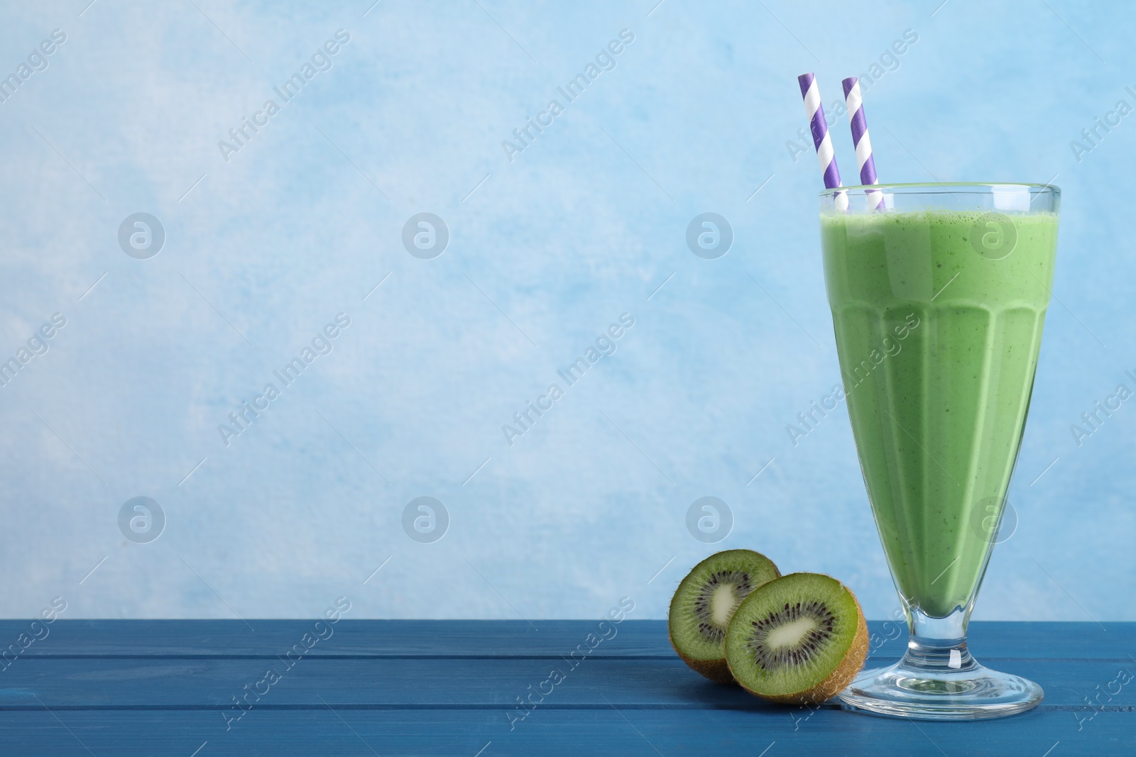 Photo of Tasty fresh kiwi smoothie on blue wooden table, space for text