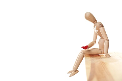 Photo of Wooden puppet with small heart sitting on table against white background. Relationship problems