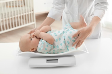 Photo of Doctor weighting baby on scales in light room