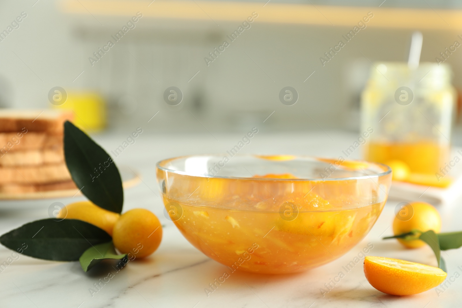 Photo of Delicious kumquat jam and fresh fruits on white marble table