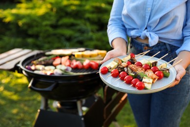 Photo of Woman with delicious grilled vegetables near barbecue grill outdoors, closeup. Space for text