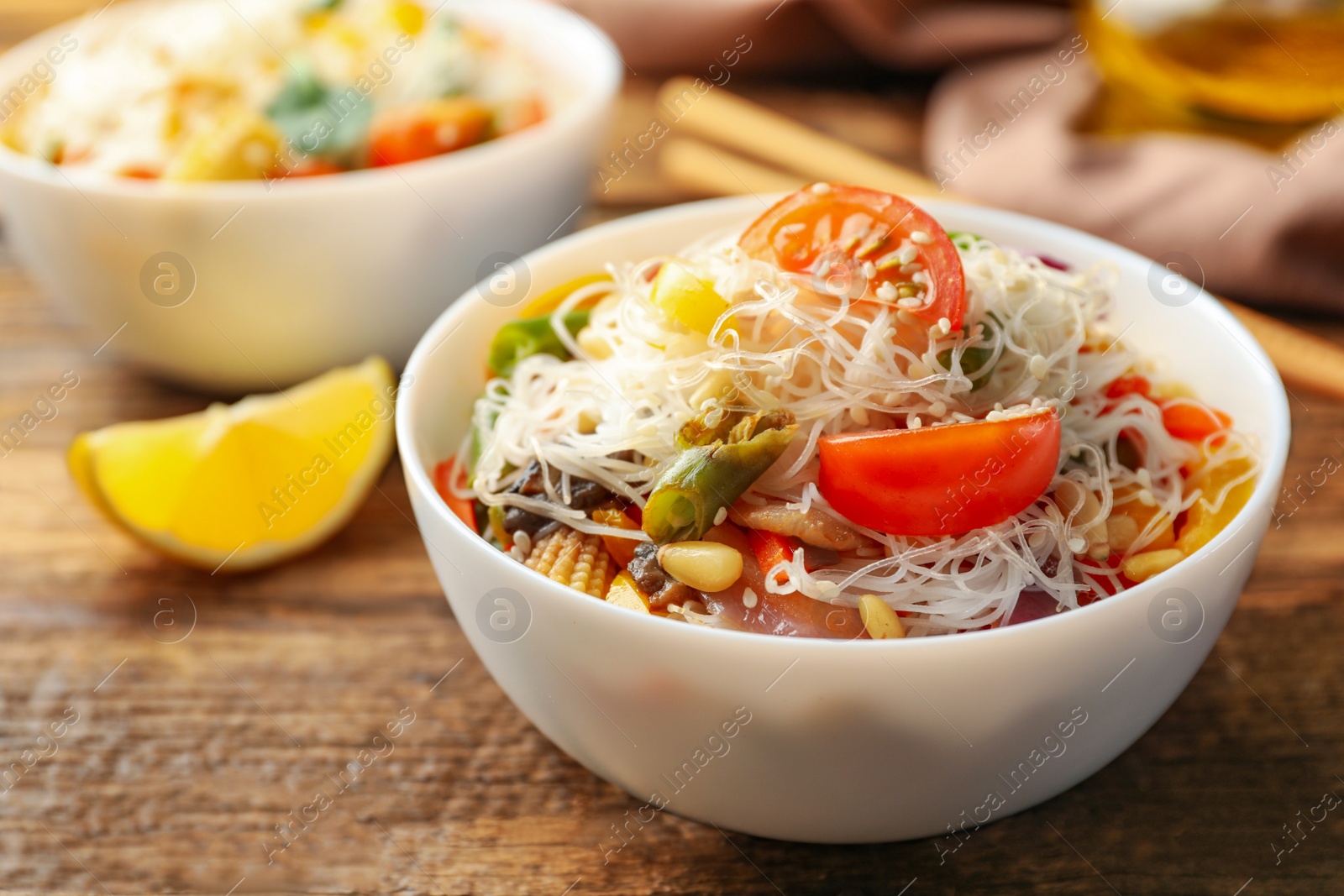 Photo of Tasty cooked rice noodles with vegetables on wooden table