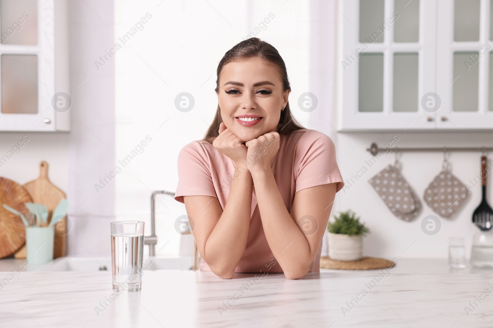 Photo of Happy woman at white marble table in kitchen