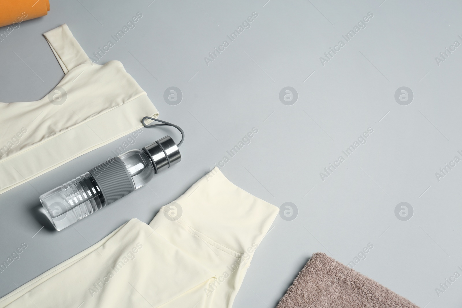 Photo of Sportswear, bottle of water and towel on grey background, flat lay with space for text. Yoga equipment