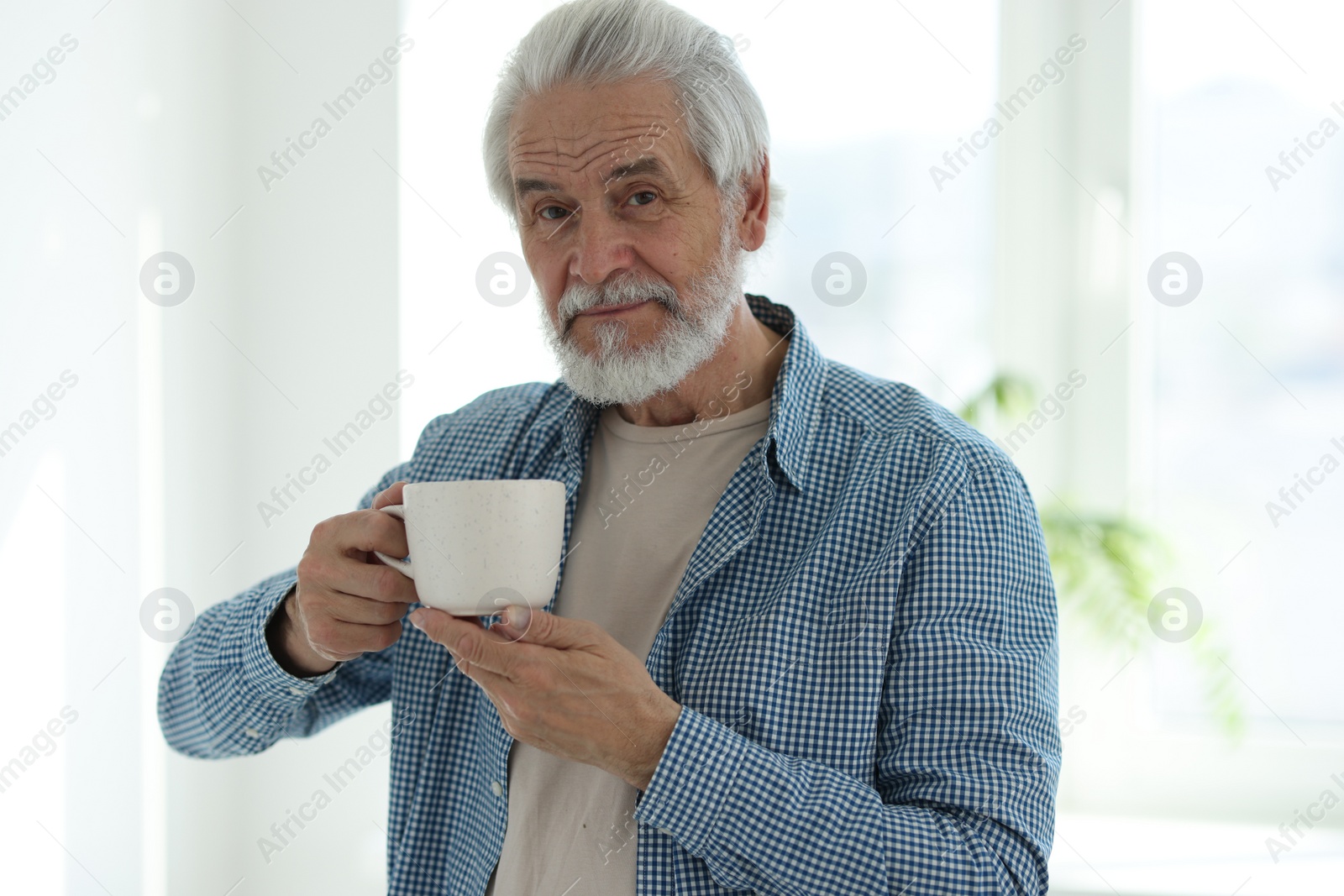 Photo of Portrait of happy grandpa with cup of drink indoors