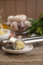 Photo of Garlic press with mince on wooden table, closeup