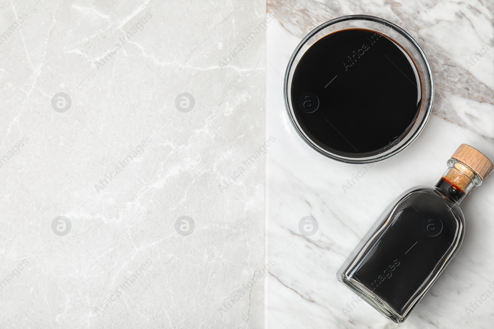 Photo of Bottle and bowl with balsamic vinegar on table, top view. Space for text