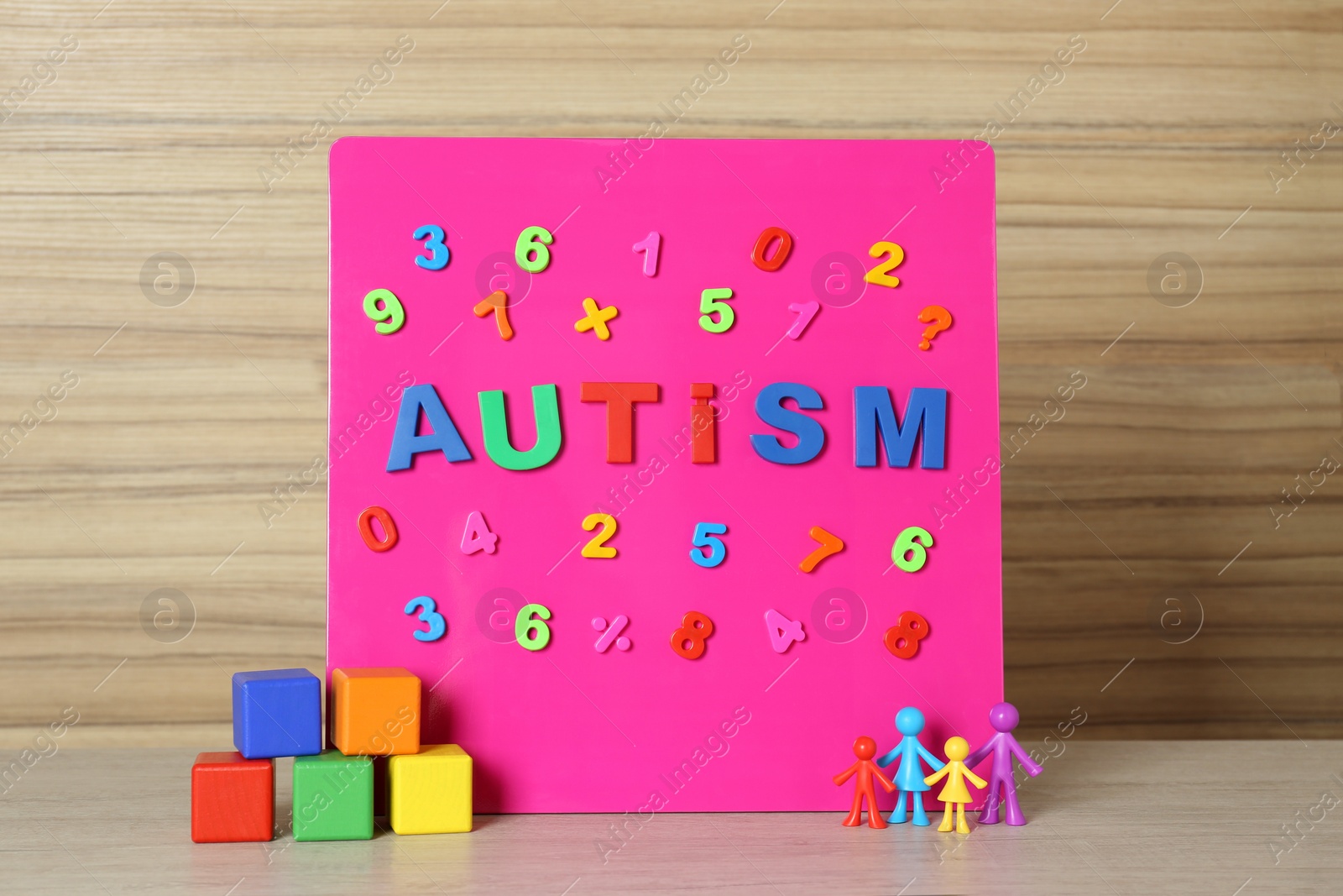 Photo of MYKOLAIV, UKRAINE - DECEMBER 30, 2021: Magnetic board with word Autism, colorful cubes and human figures on wooden table