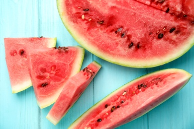 Photo of Tasty ripe cut watermelon on light blue wooden table, flat lay