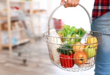 Photo of Man with shopping basket full of products in grocery store, closeup