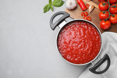 Flat lay composition with delicious tomato sauce on light grey table, space for text