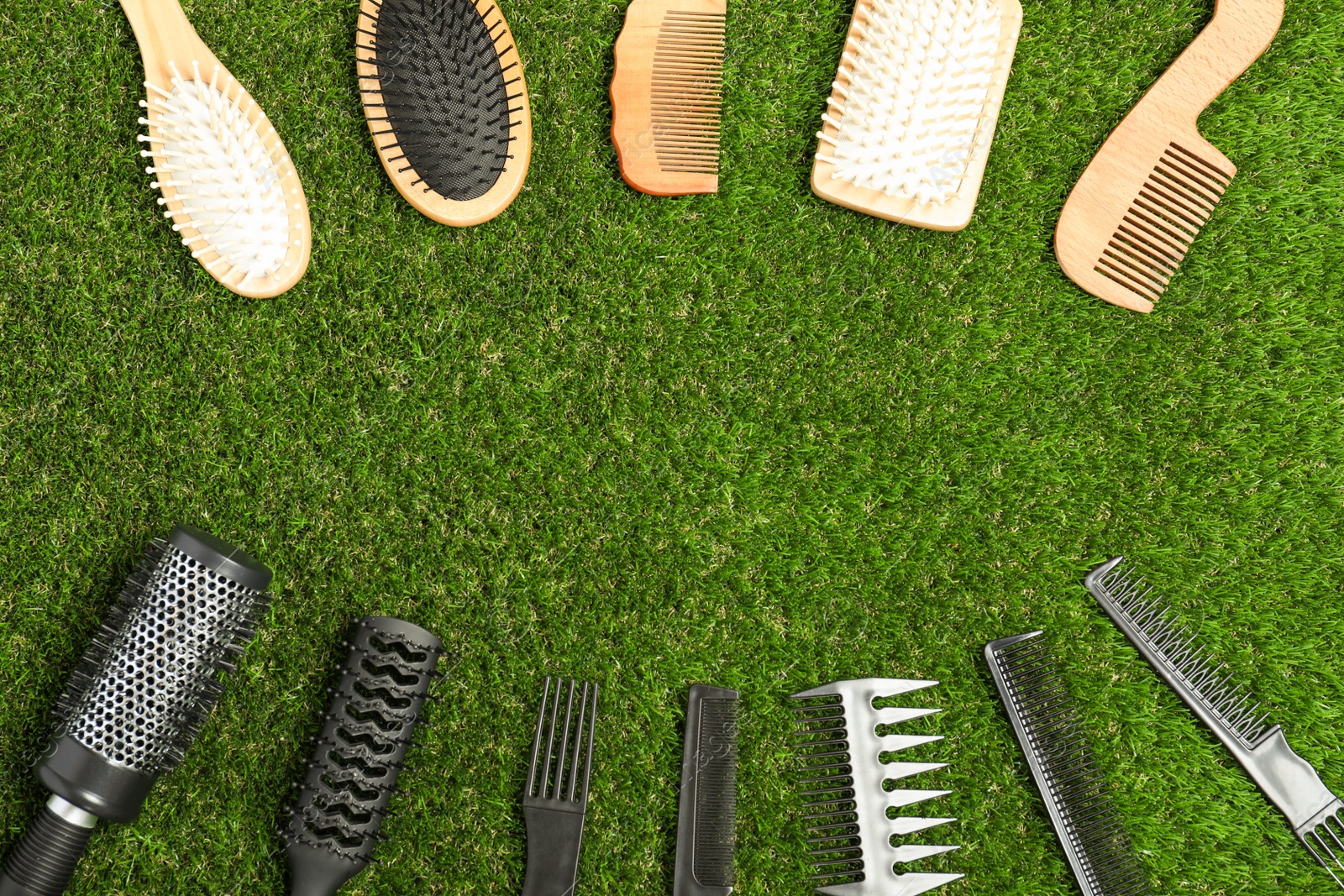 Photo of Flat lay composition with plastic and wooden hairbrushes on green grass, space for text. Recycling concept