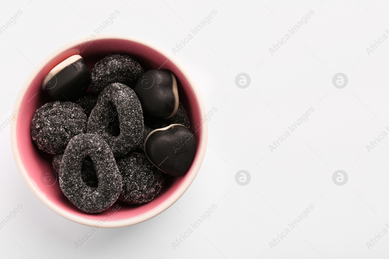 Photo of Bowl of tasty liquorice candies on light background, top view. Space for text