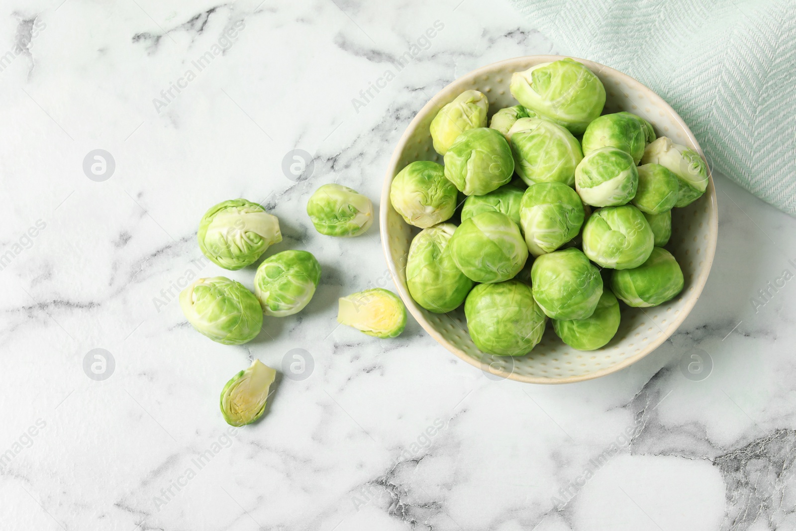 Photo of Bowl with fresh Brussels sprouts on marble table, top view. Space for text