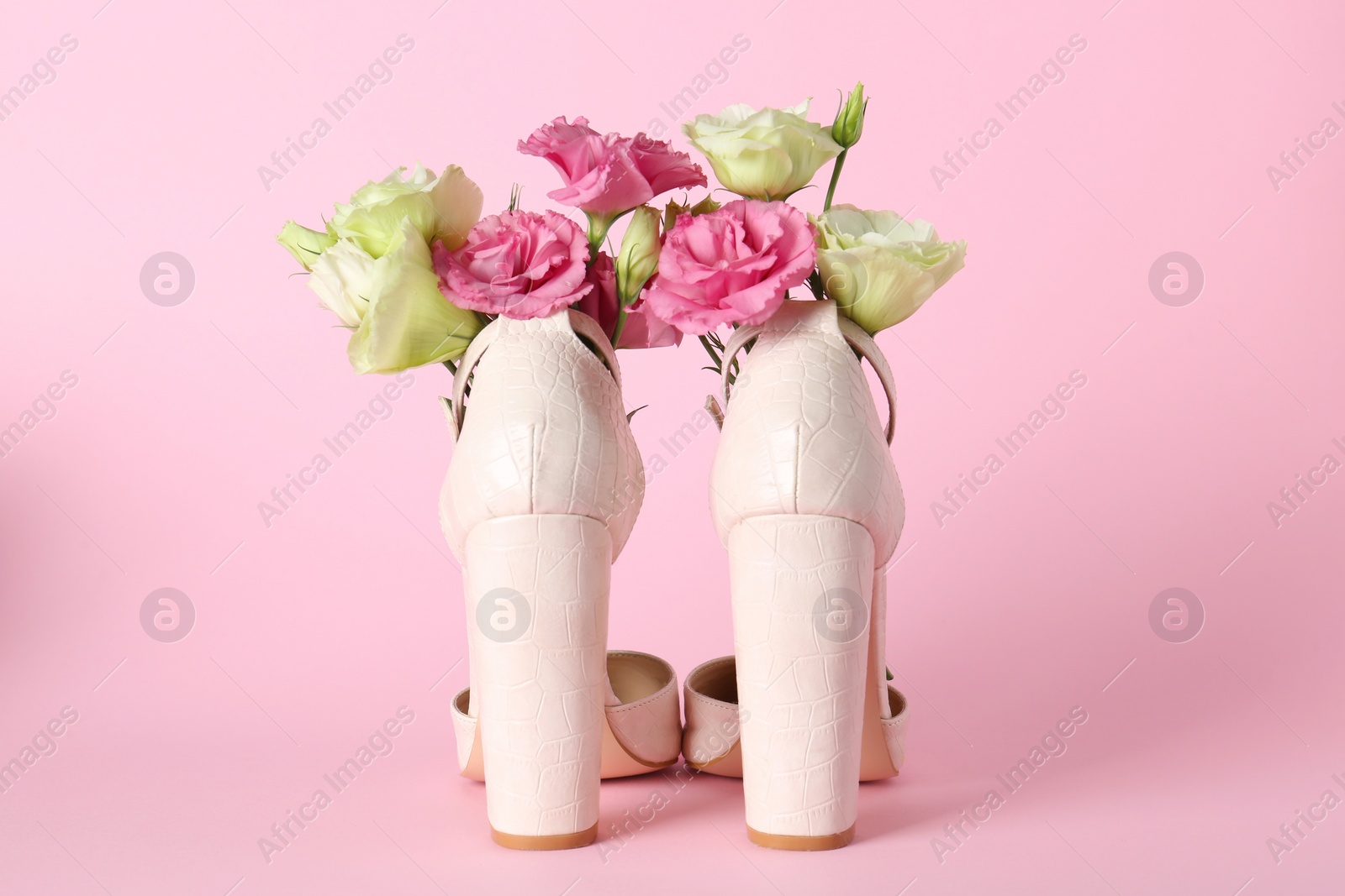 Photo of Stylish women's high heeled shoes with beautiful flowers on pink background