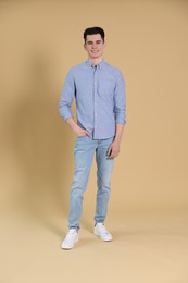 Full length portrait of handsome young man on beige background
