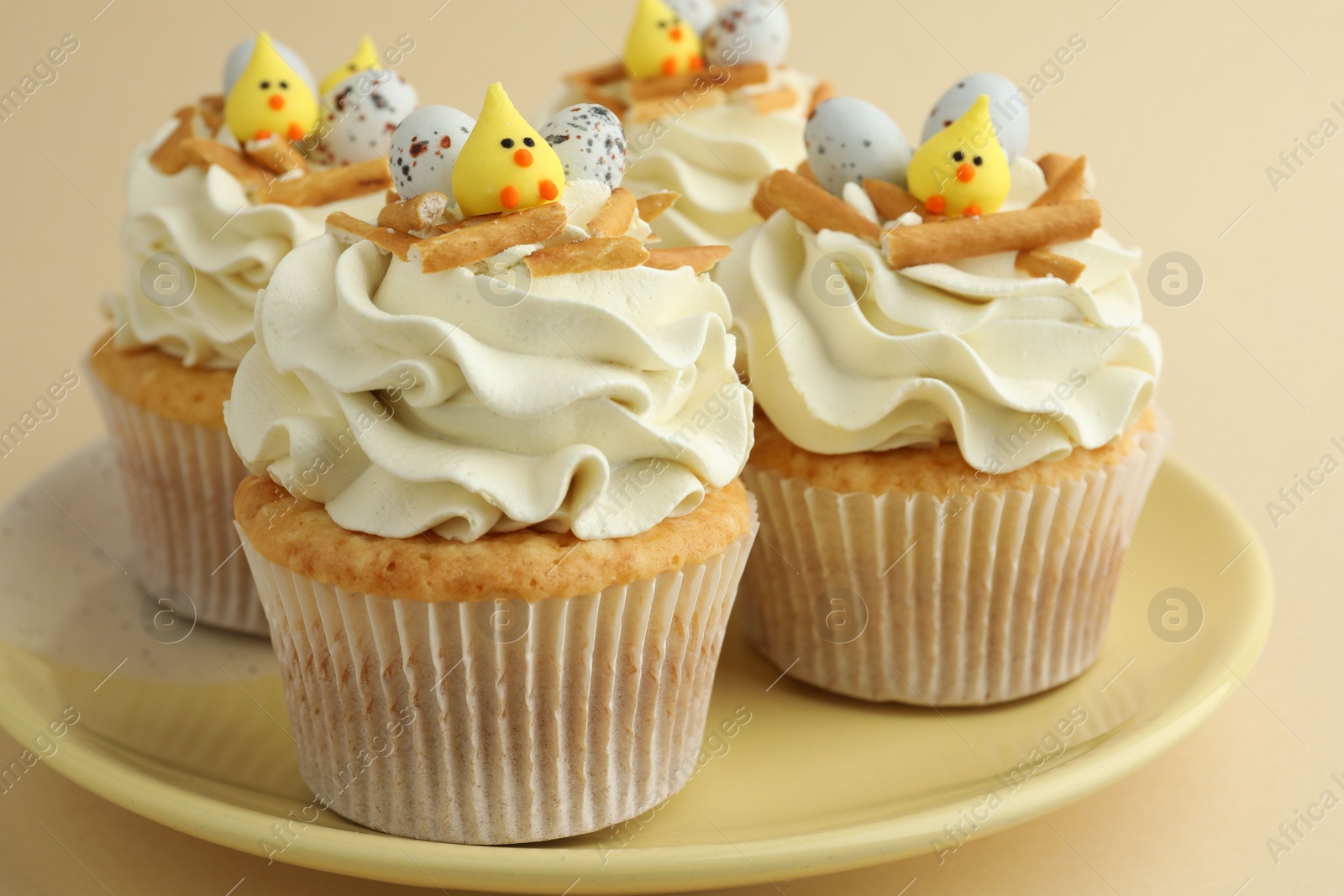 Photo of Tasty Easter cupcakes with vanilla cream on beige background, closeup