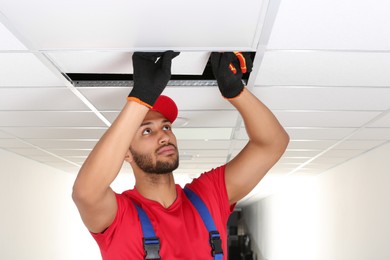 Photo of Electrician with pliers repairing ceiling light indoors, space for text
