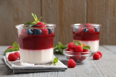 Photo of Delicious panna cotta with berries on grey wooden table