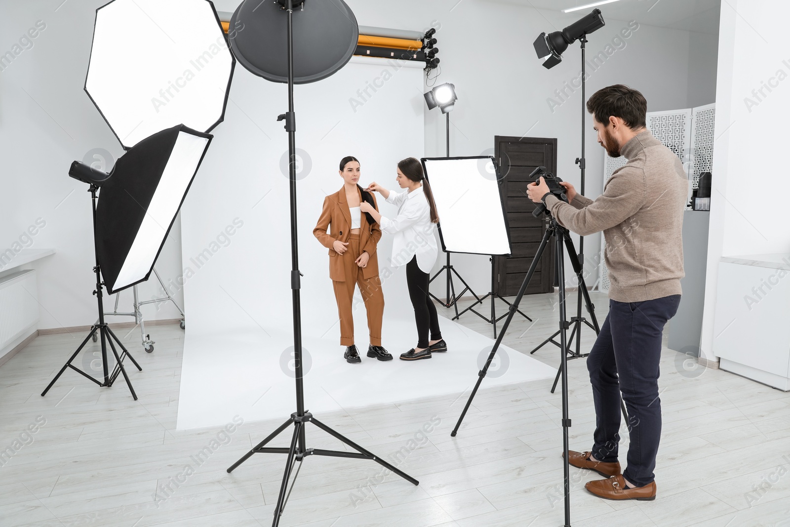 Photo of Professional photographer and stylist working with beautiful model in modern photo studio