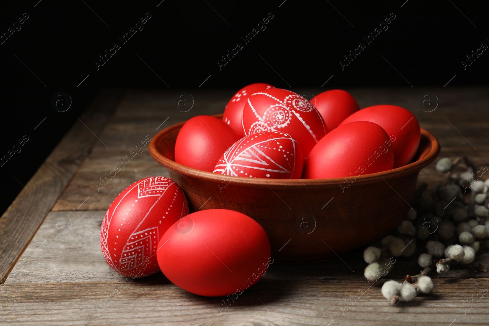 Photo of Wooden bowl with red painted Easter eggs on table