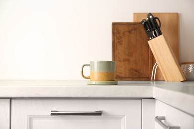 Photo of One ceramic mug with coaster on light countertop in kitchen