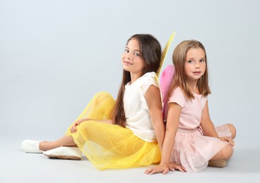 Photo of Cute little girls in fairy costumes with wings on light background
