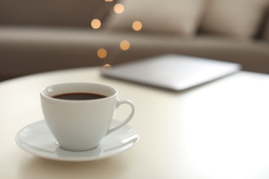 Cup of coffee on table indoors, space for text. Bokeh effect