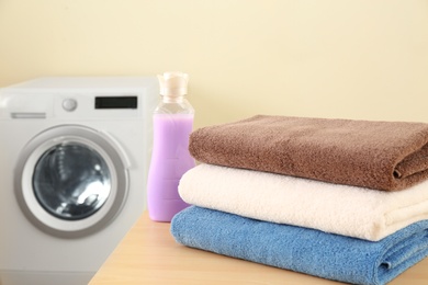 Photo of Clean towels and bottle of detergent on table in laundry room. Space for text