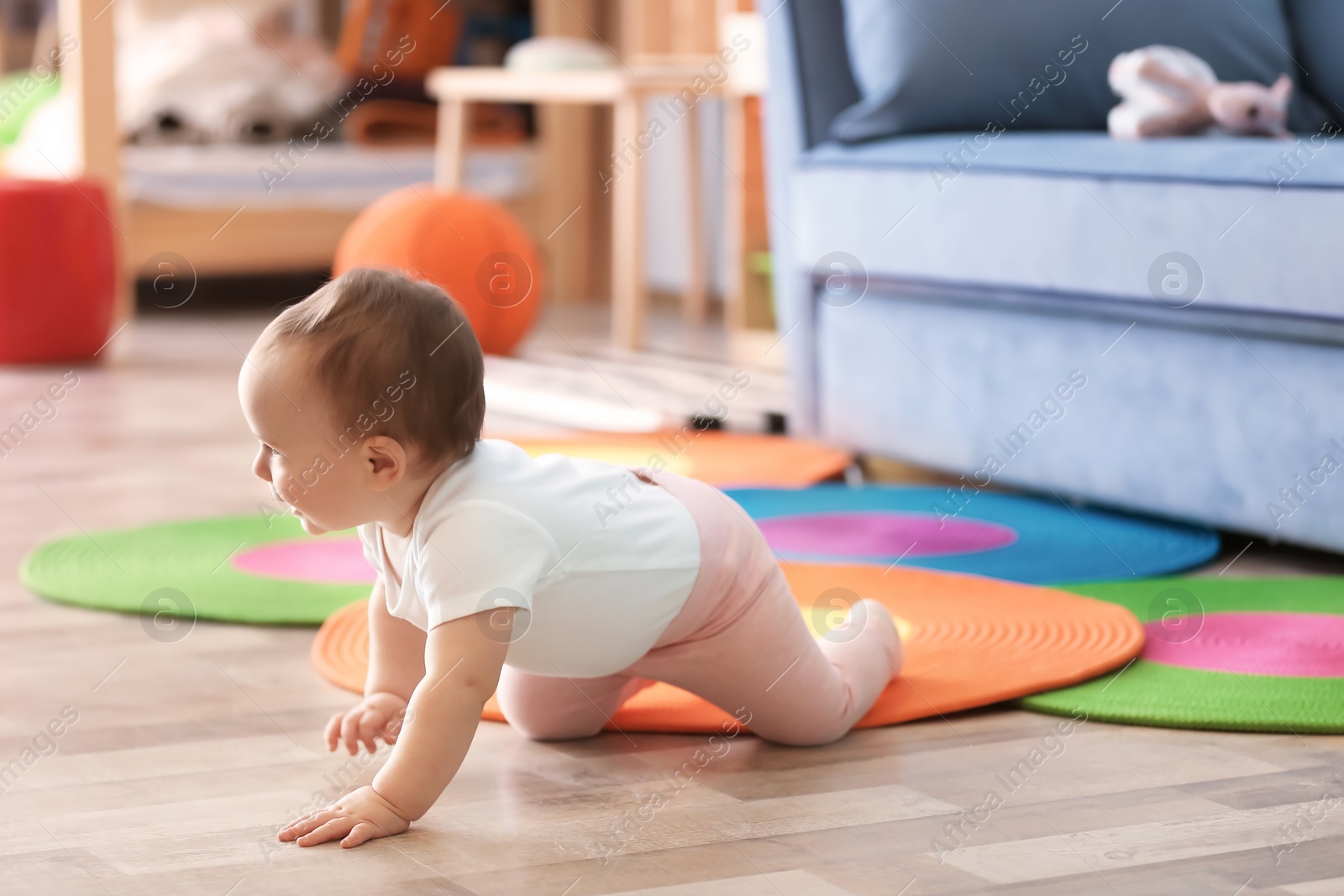 Photo of Cute baby crawling on floor in living room