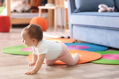 Cute baby crawling on floor in living room