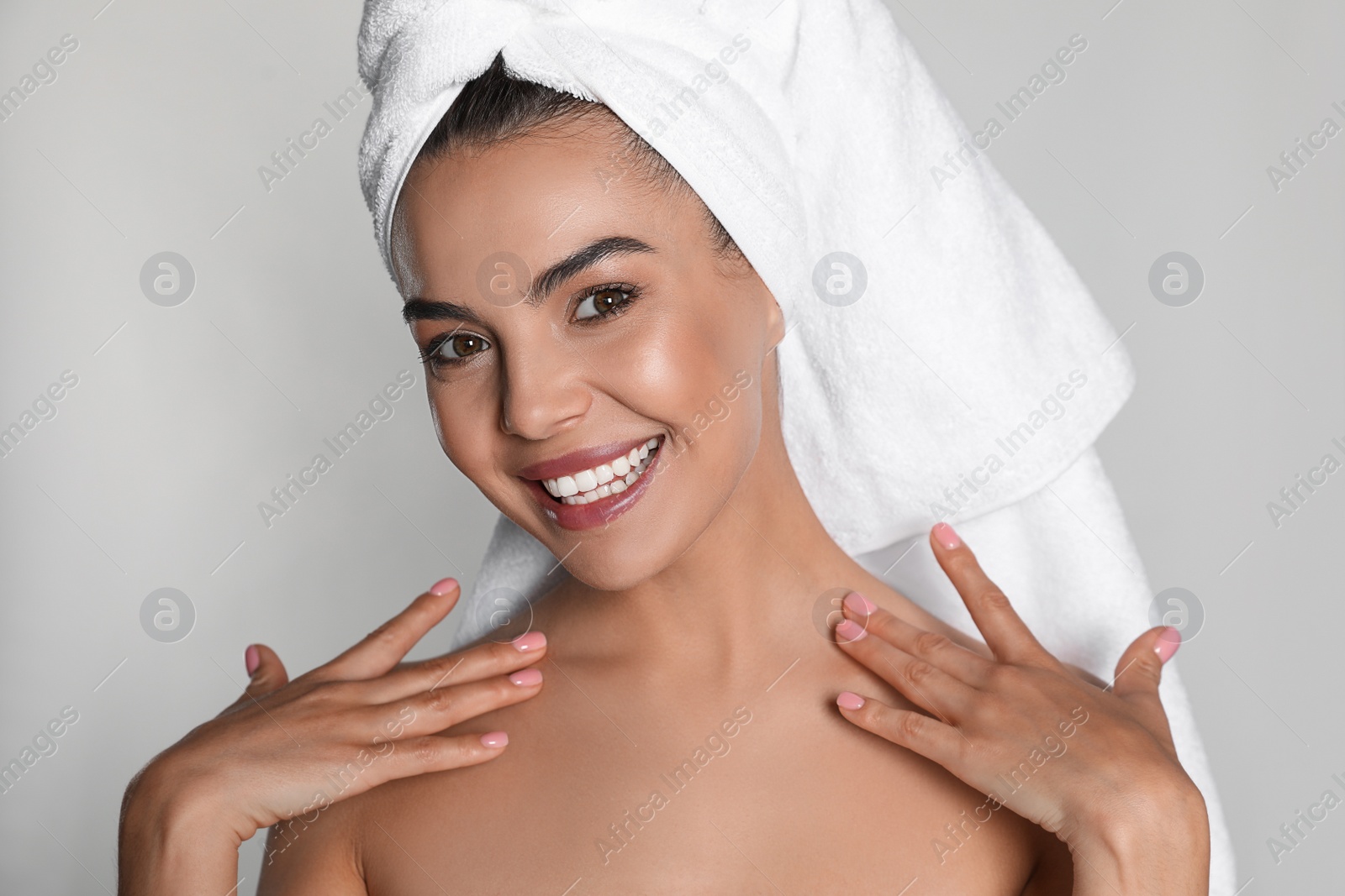 Photo of Beautiful young woman with towel on head against light background