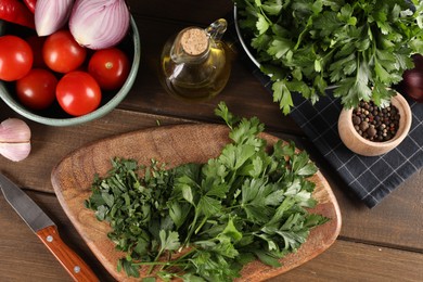 Fresh green parsley and different products on wooden table, flat lay