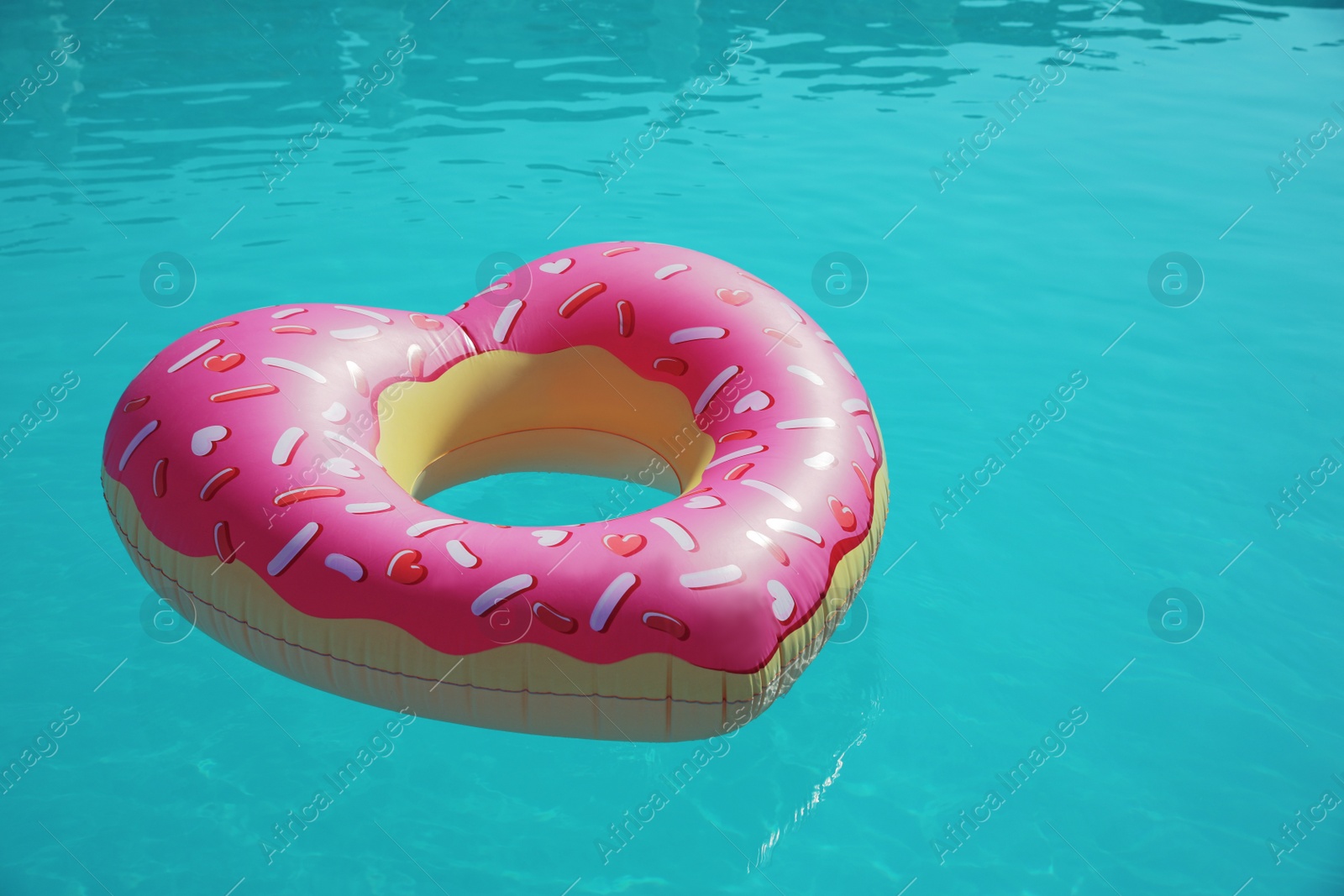 Photo of Heart shaped inflatable ring floating in swimming pool on sunny day