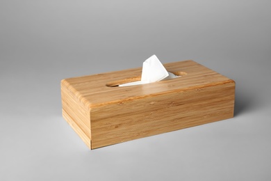 Photo of Wooden napkin holder with paper serviettes on gray background