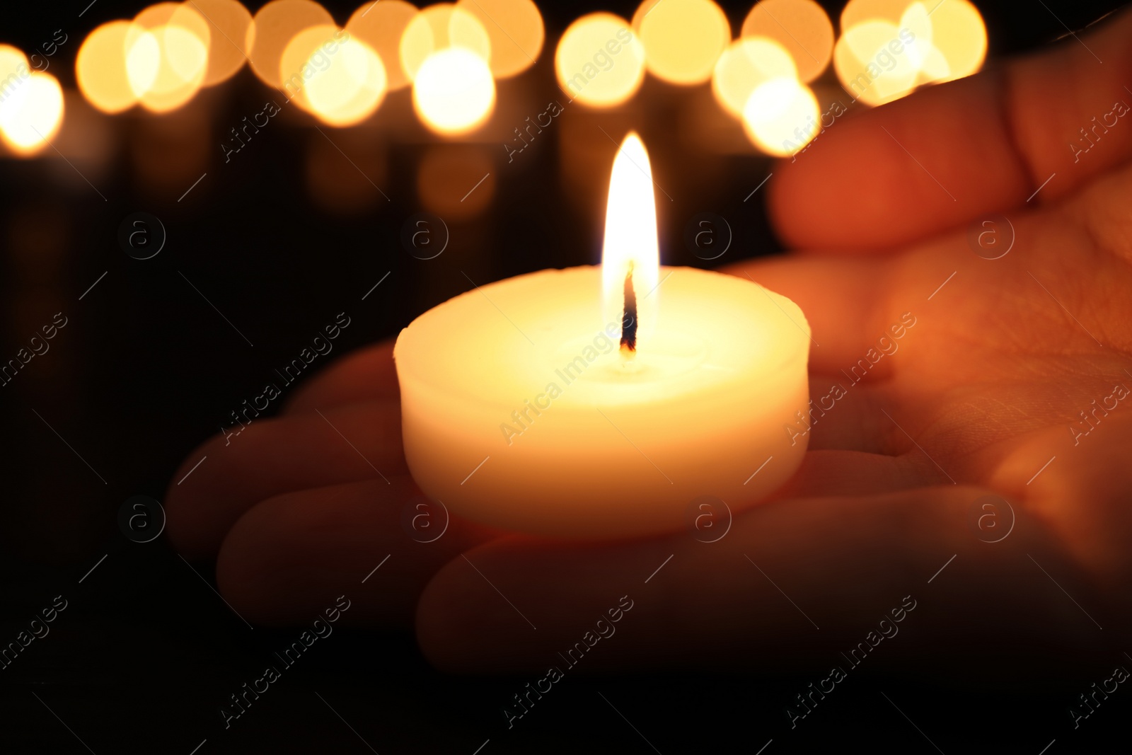 Photo of Woman with burning candle in darkness, closeup. Memory day