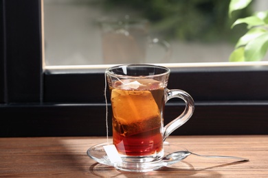 Photo of Glass cup of hot tea on wooden window sill