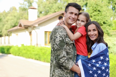 Photo of Man in military uniform and his family with American flag outdoors