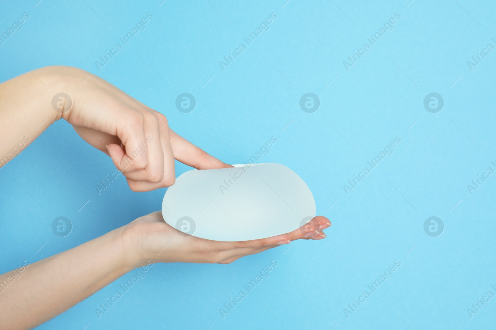 Photo of Woman touching silicone implant for breast augmentation on color background, space for text. Cosmetic surgery