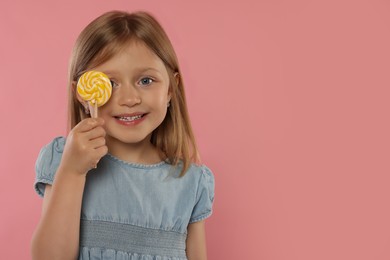 Photo of Portrait of happy girl with lollipop on pink background, space for text
