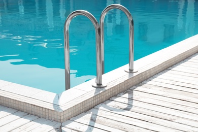 Modern swimming pool with ladder at resort
