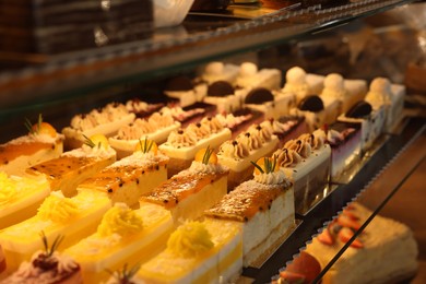 Different delicious cakes on counter in bakery shop, closeup