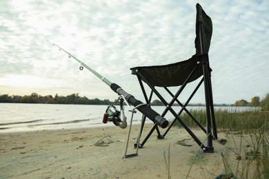 Photo of Folding chair and fishing rod at riverside, low angle view