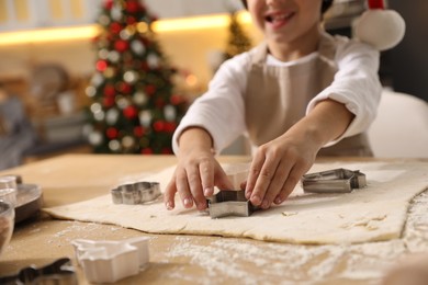Photo of Little boy making Christmas cookies in kitchen, closeup