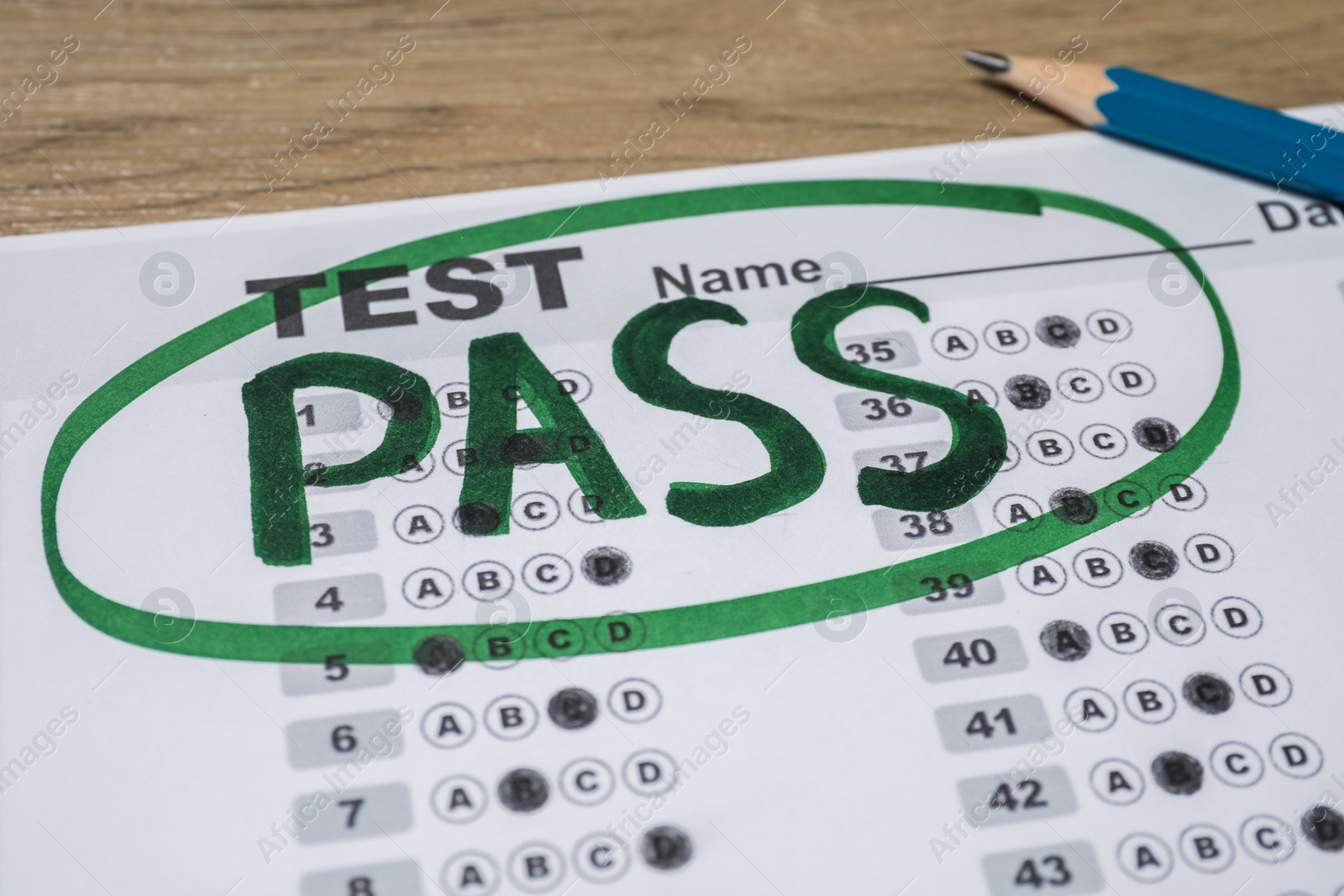 Photo of Answer sheet with word Pass and pencil on wooden table, closeup. Student passing exam