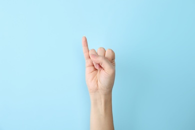 Photo of Woman showing I letter on color background, closeup. Sign language