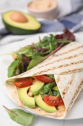 Photo of Plate with hummus wrap and vegetables on white table