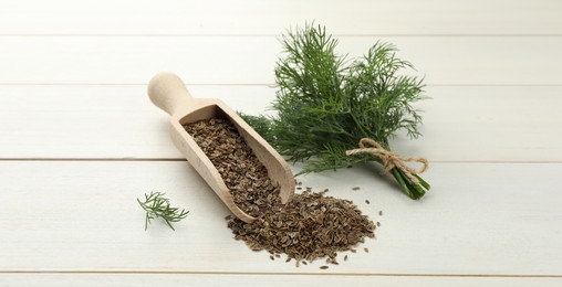 Image of Dill seeds in scoop and bunch of fresh green dill on white wooden table. Banner design