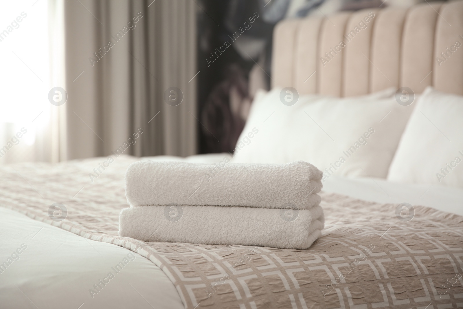 Photo of Clean white towels on bed at home